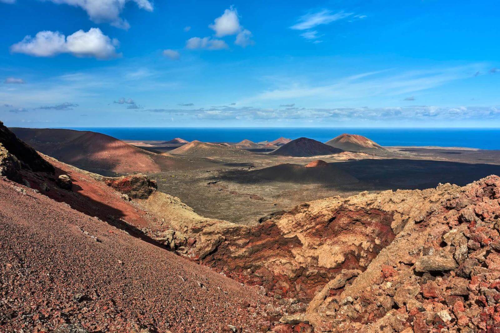 Vulkaanlandschap met lavastromen, bergen en zee op de achtergrond in Nationaal Park Timanfaya, Lanzarote.