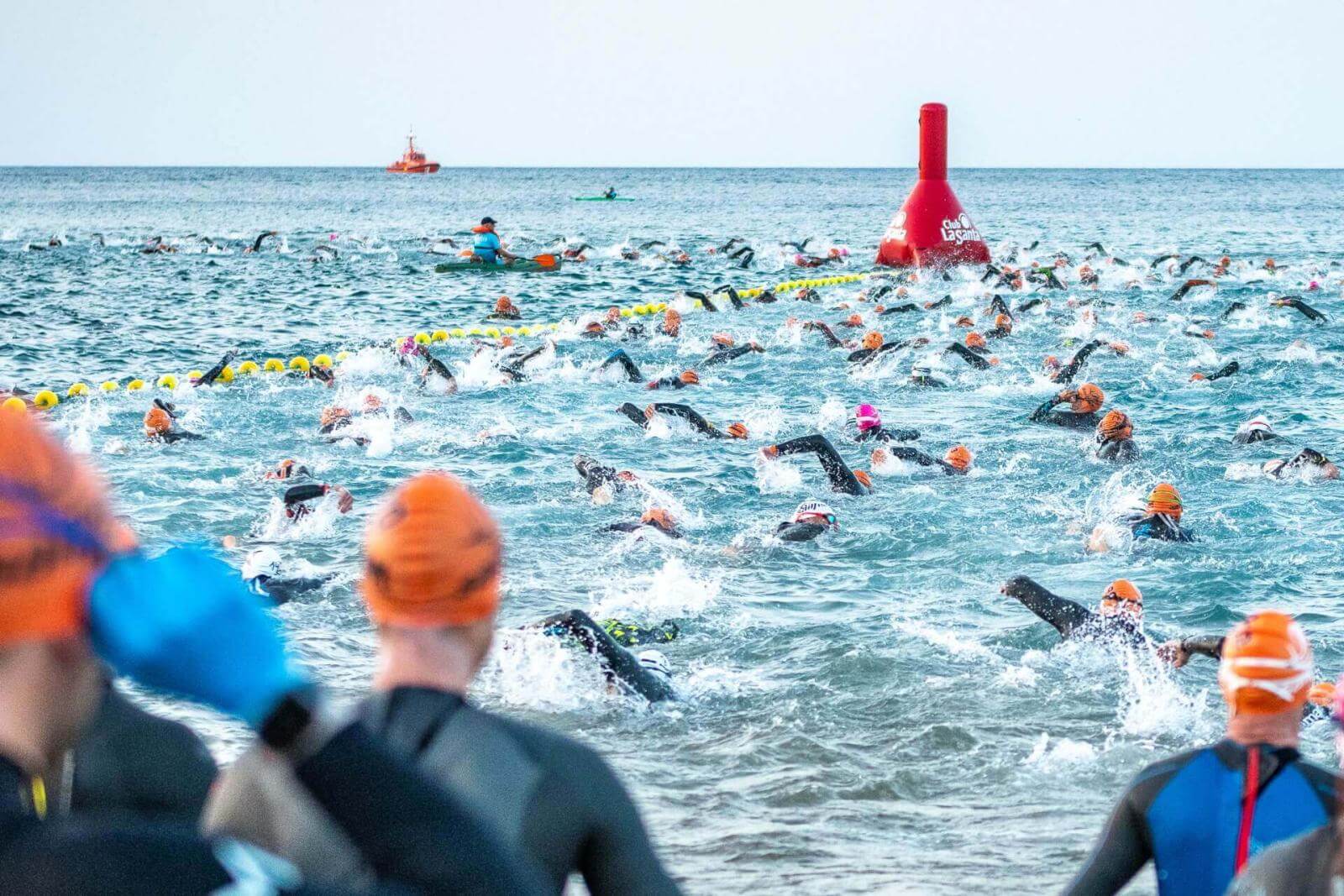 Groep zwemmers tijdens een wedstrijd in open water op een met boeien afgezet parcours.