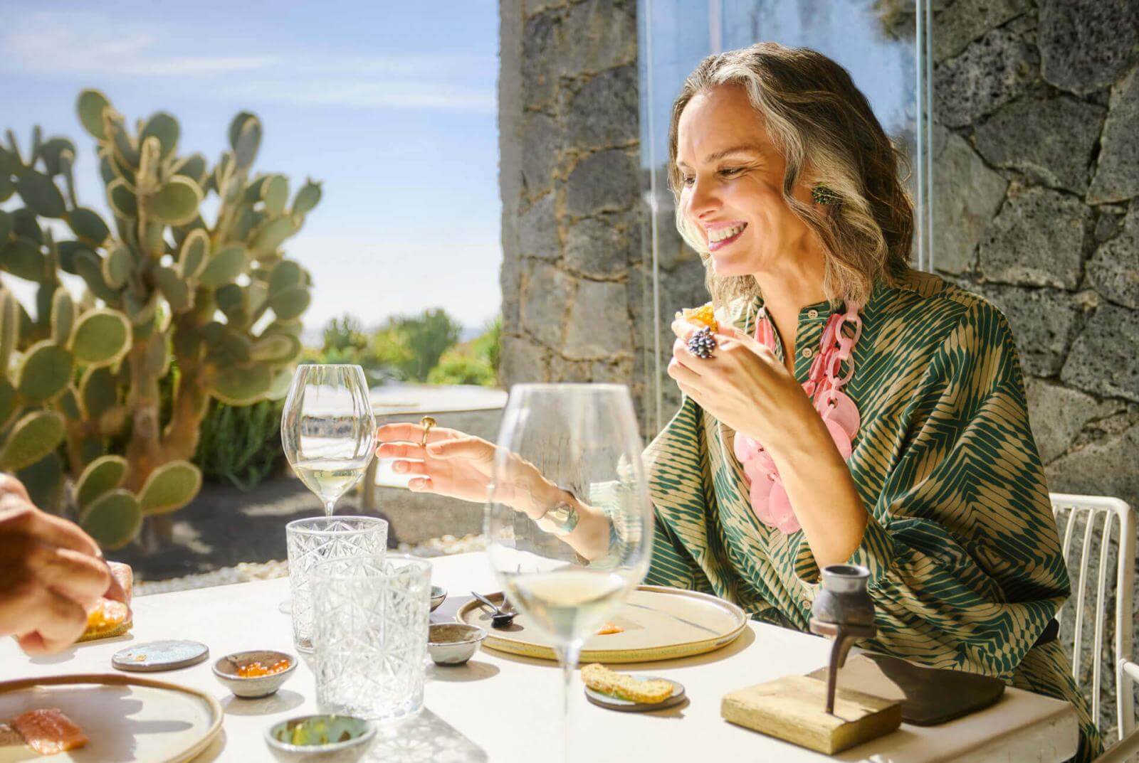 Genietend van een aperitief en een glas wijn aan een tafel bij de terrasdeur met cactussen op de achtergrond.