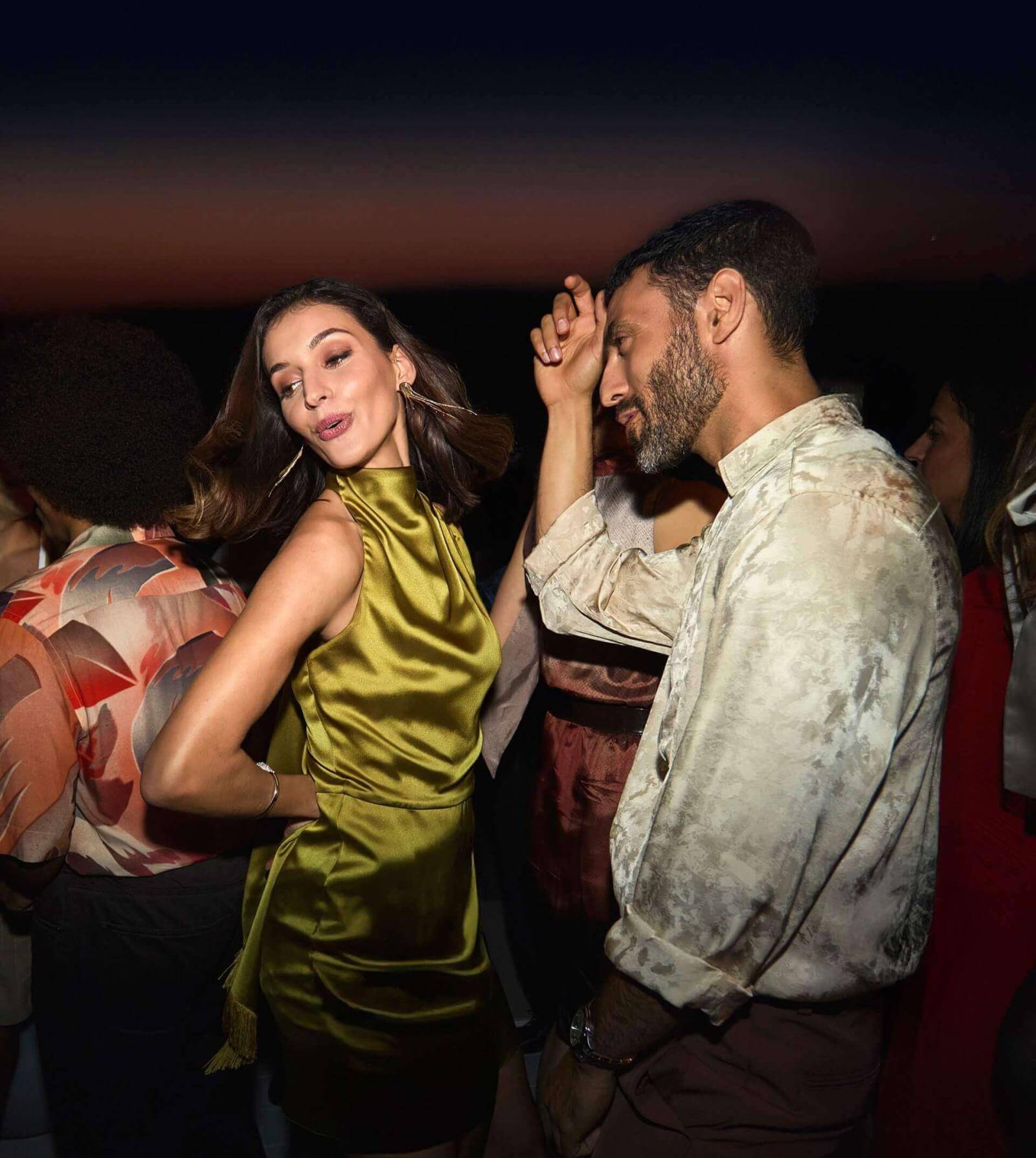 Stel dansend op een dakterras met uitzicht op zee bij zonsondergang.