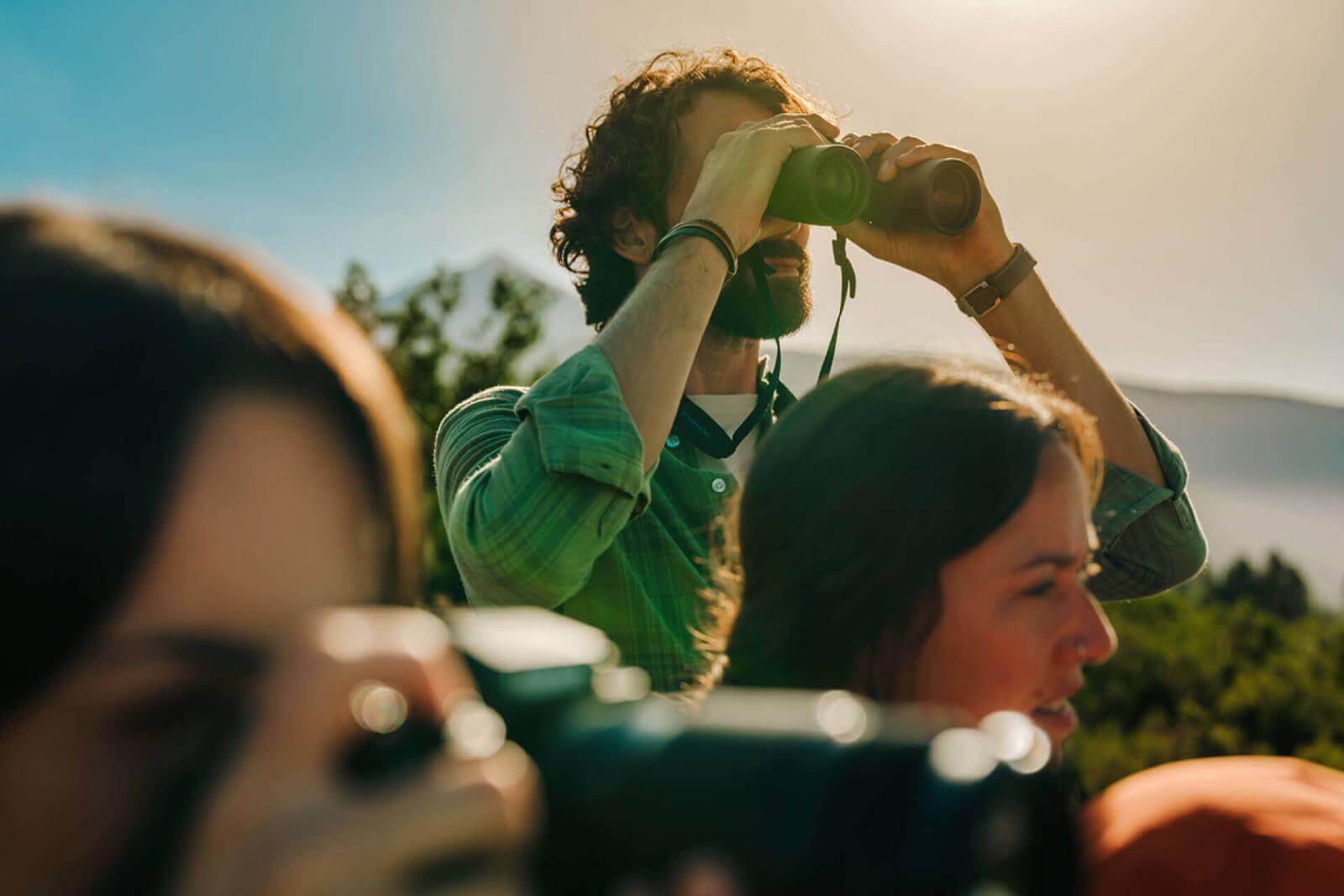 Groep observeert het landschap - één persoon met een verrekijker en een andere met een camera op de voorgrond.