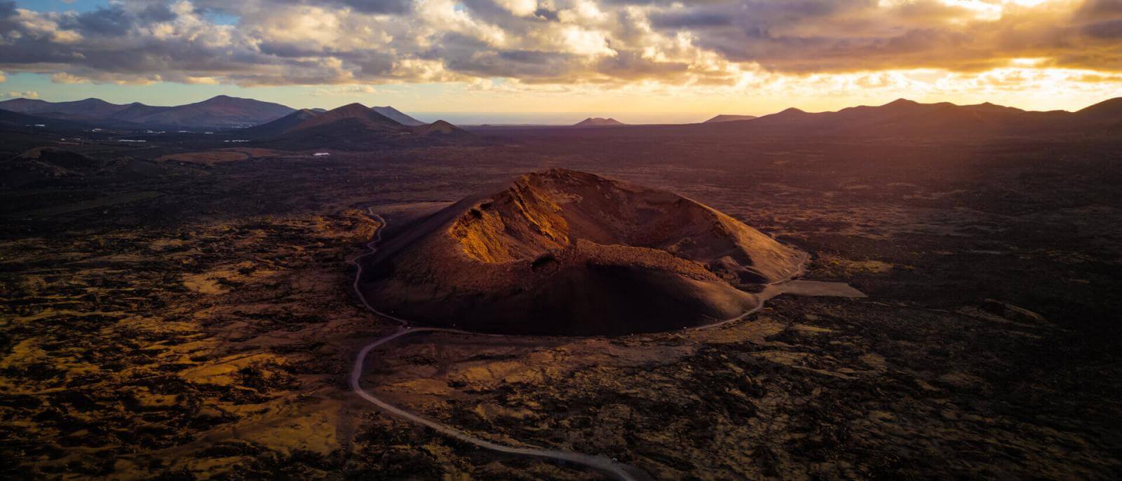 Luchtfoto van Vulkaan van El Cuervo, met de krater verlicht bij zonsondergang en een vulkaanlandschap.
