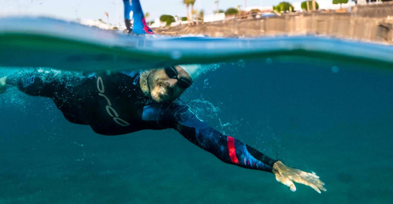 Persoon die in open water zwemt met een wetsuit.