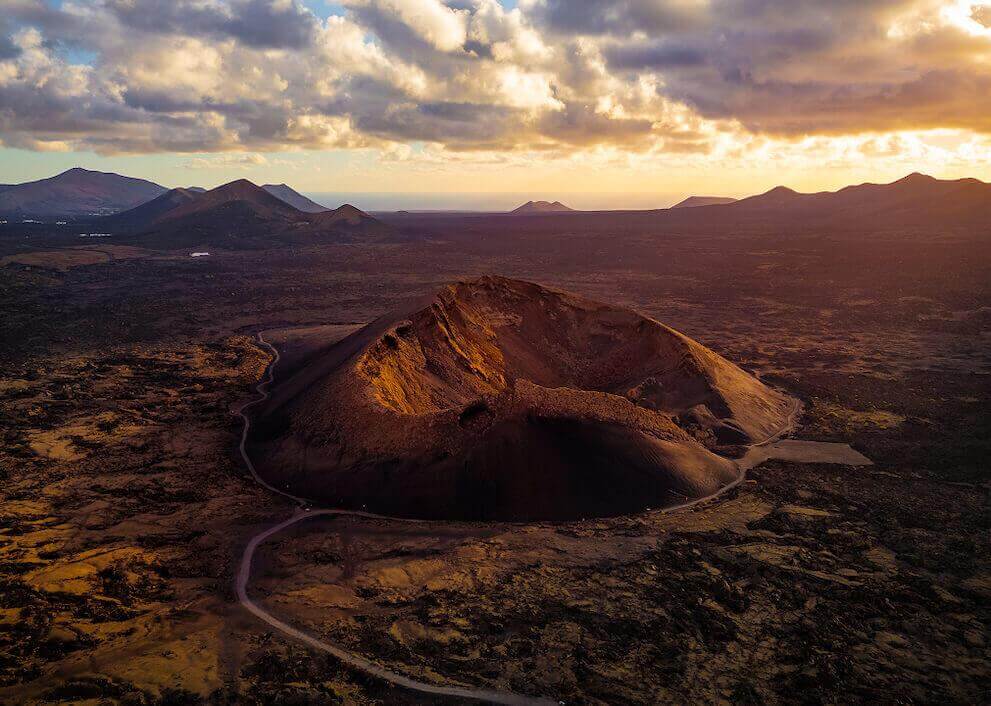 Luchtfoto van Vulkaan van El Cuervo, met de krater verlicht bij zonsondergang en een vulkaanlandschap.